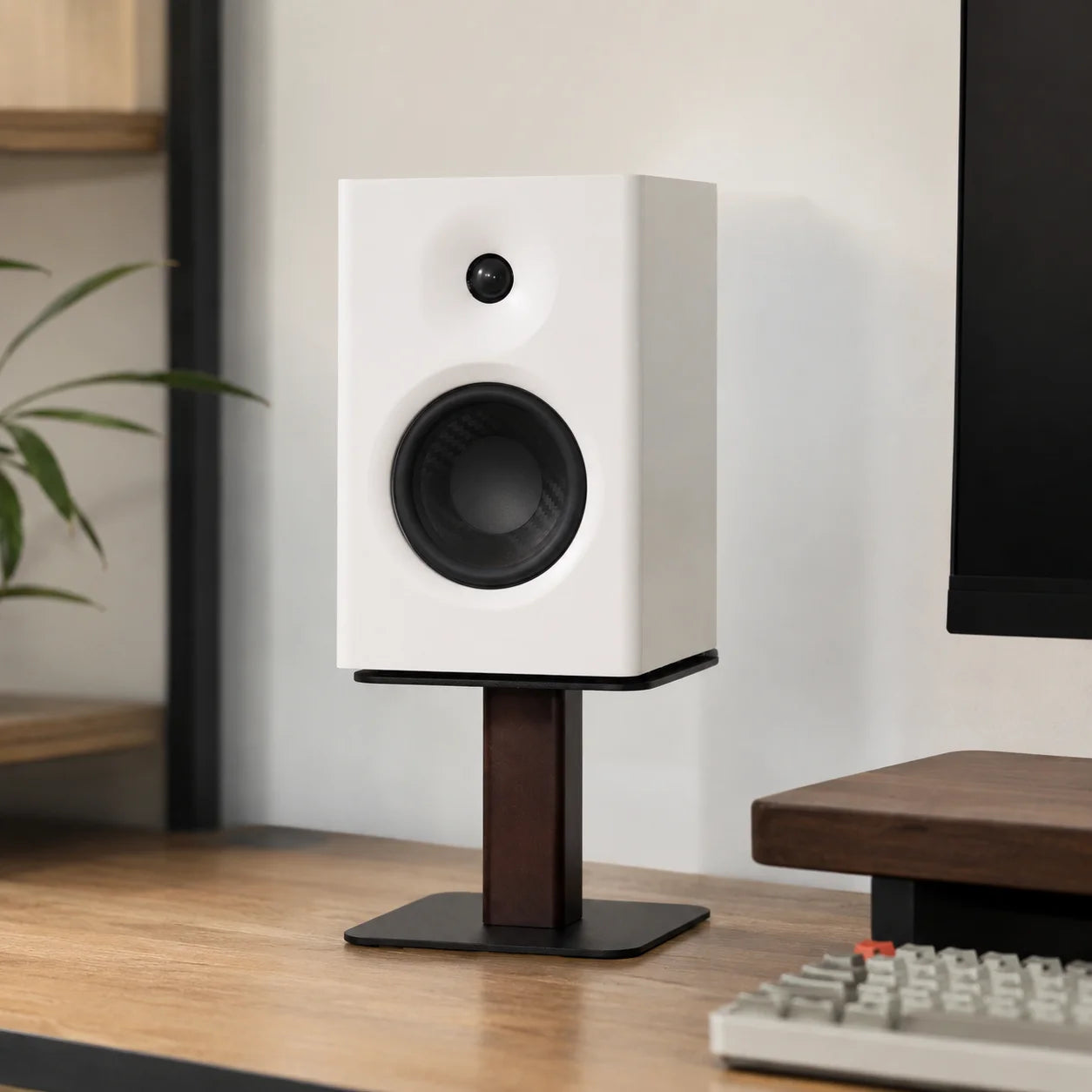 Enceinte compacte blanche sur support bois-noir, bureau moderne avec moniteur et clavier mécanique